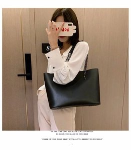 Detail of a black leather tote bag with stylish metal chain strap for women