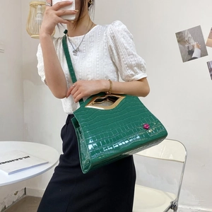Sac à main vert à motif crocodile avec poignée à lèvres dorée et détail à lèvres rose