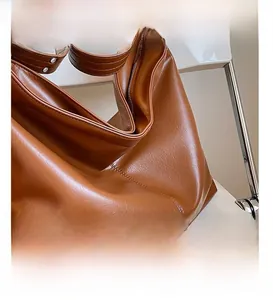 Détails des coutures précises et des rivets métalliques sur le sac cabas en cuir marron