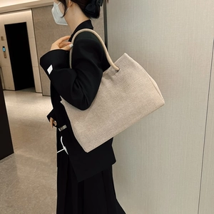 Detail view of large canvas tote bag with woven rope handle and silver metal eyelets