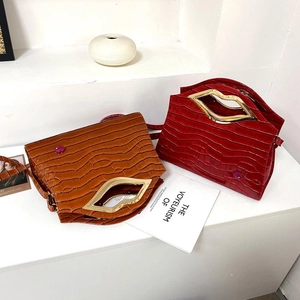Détail du sac à main gaufré crocodile avec poignée métallique dorée en forme de lèvres