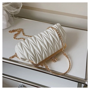 Detail of white matelassé pleated handbag with gold metal frame and ball clasp closure