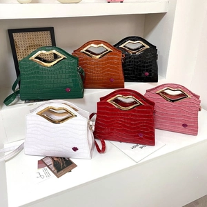 Détail de sacs à main texturés crocodile avec des poignées dorées uniques en forme de lèvres