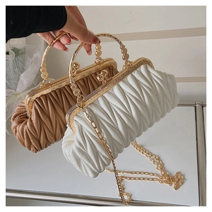 Detailed view of quilted leather texture and gold ring handle on a luxury pleated handbag