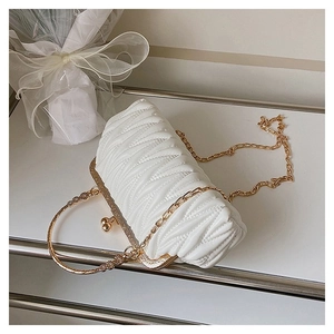 Detail of white quilted pleat clutch bag with gold kiss-lock and pearl handle