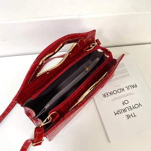 Détail du sac à main rouge texture crocodile avec poignée dorée et intérieur spacieux
