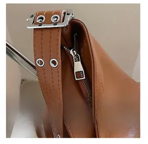 Détail de la fermeture éclair et de la boucle métallique sur le sac en cuir marron