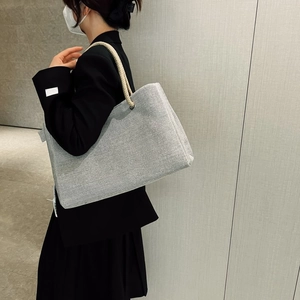 Close-up of grey woven tote bag with rope handles and large capacity on a model