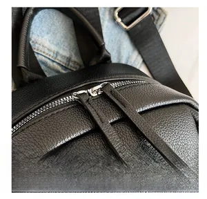 Détail des fermetures éclair argentées et du cuir grainé litchi sur un sac à dos noir