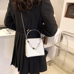 White textured vertical handbag with geometric embossing and heart chain crossbody strap
