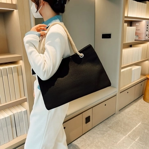 Detail of black canvas tote bag with thick cotton rope handles and silver metal eyelets