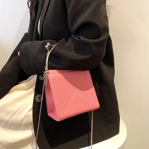 Bright pink fashion handbag with V-shaped stitching and metallic handle on a female model