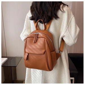 Détail de la texture en cuir grainé du sac à dos marron et poche latérale sur le modèle