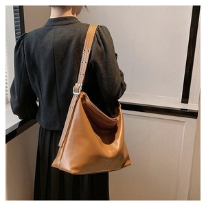 Sac hobo vintage en cuir marron avec bandoulière cloutée porté par un mannequin