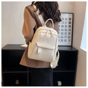 Détail du sac à dos blanc à motif litchi montrant zips en métal et poche à rabat