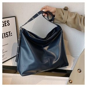 Détail du sac cabas bleu marine en cuir avec œillets argentés et bandoulière réglable