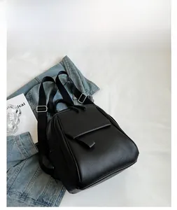 Détail d'un sac à dos noir en cuir grainé avec boucles argentées et poche frontale