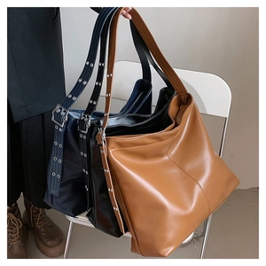 Détail de trois grands sacs cabas en similicuir en marron, noir et bleu avec boucles métal