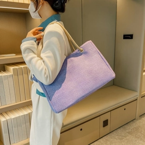 Detail of purple canvas tote bag featuring thick rope handles and silver metal grommets