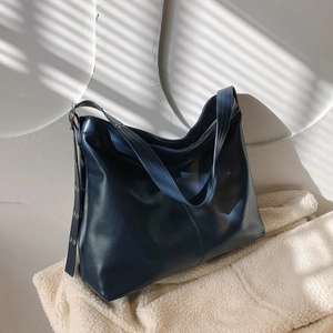 Détail du sac fourre-tout bleu marine en similicuir souple avec boucle argentée sur fond blanc
