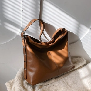 Détail du sac cabas en cuir caramel avec œillets métalliques et bandoulière réglable