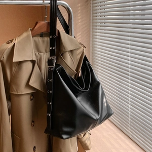 Détail de la bandoulière large avec œillets argentés et boucle sur sac noir