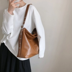 Détail d'un grand sac hobo marron avec bandoulière large et œillets métalliques décoratifs