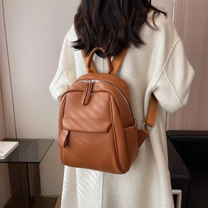 Sac à dos femme en cuir marron grainé porté par un mannequin dans un cadre minimaliste