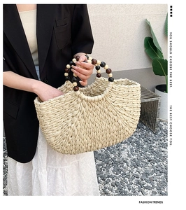 Detail of hand-woven beige bag featuring a unique wooden bead handle with black and brown accents