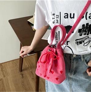 Detailed view of rose pink drawstring bucket bag with red heart embroidery and strap