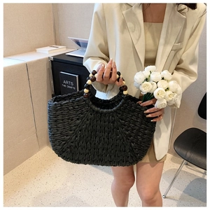 Detail of black woven straw handbag featuring vintage style wooden beaded round handles