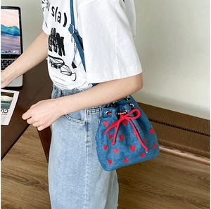 Blue denim bucket bag with red heart embroidery and drawstring closure detail