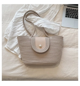 Détail du sac cabas en paille tressée avec fermoir perle et rabat décoratif en cuir