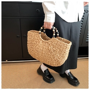 Detail of woven straw handbag featuring bohemian tricolor wood beaded handles