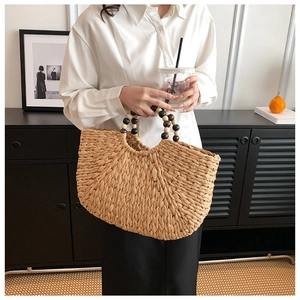 Detail of hand-woven straw handbag featuring vintage wooden bead handles and rustic texture