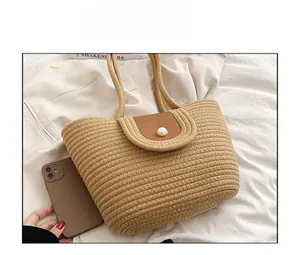 Détail du sac à main en paille avec rabat en cuir marron et boucle décorative en perle