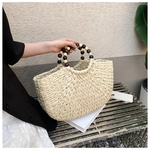 Detail of hand-woven cream tote bag with decorative dark brown wooden bead handles