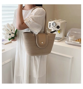 Détail du sac cabas en paille avec rabat en cuir et boucle en perle dans un café