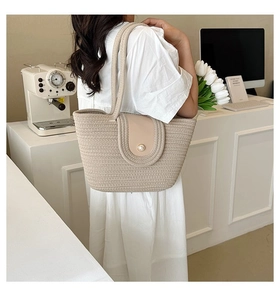 Détail du sac cabas en paille crème avec rabat en cuir et bouton perle élégant