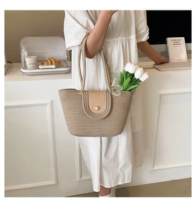 Détail du sac cabas en paille beige avec rabat en cuir et fermeture bouton perle chic