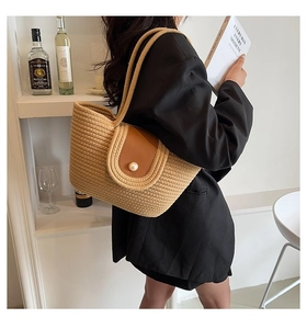Détail du sac à bandoulière en paille tissée avec rabat en cuir et boucle en perle élégante