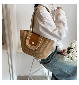 Détail du sac à main en paille avec rabat en cuir marron et fermeture à bouton perle