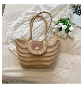 Détail du sac cabas en paille tressée avec rabat en cuir et bouton perle élégant