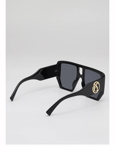 Detail of square sunglasses showing thick black frame and golden S-shaped metal logo