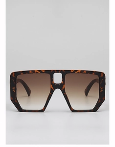 Close-up of oversized tortoiseshell sunglasses featuring gold metal hinge detail