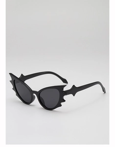 Detail view of glossy black bat-shaped sunglasses with jagged gothic frames for parties