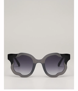 Detail of irregular wave-edged oversized sunglasses with purple gradient lenses
