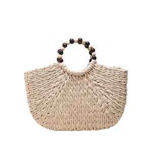 Elegant hand-woven straw tote bag with round wooden beaded handles in a fan-shaped silhouette