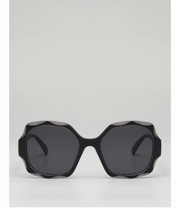 Detail of stylish oversized black sunglasses featuring a unique wavy frame design