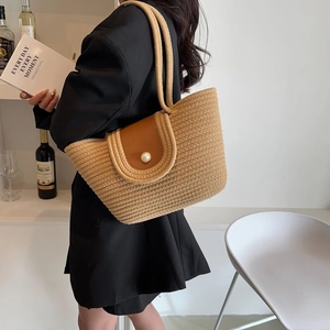 Sac à main en paille avec rabat en cuir marron et boucle perle sur un mannequin